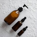 Black Friday beauté 2026 : trois flacons ambrés de soin posés sur du marbre blanc
