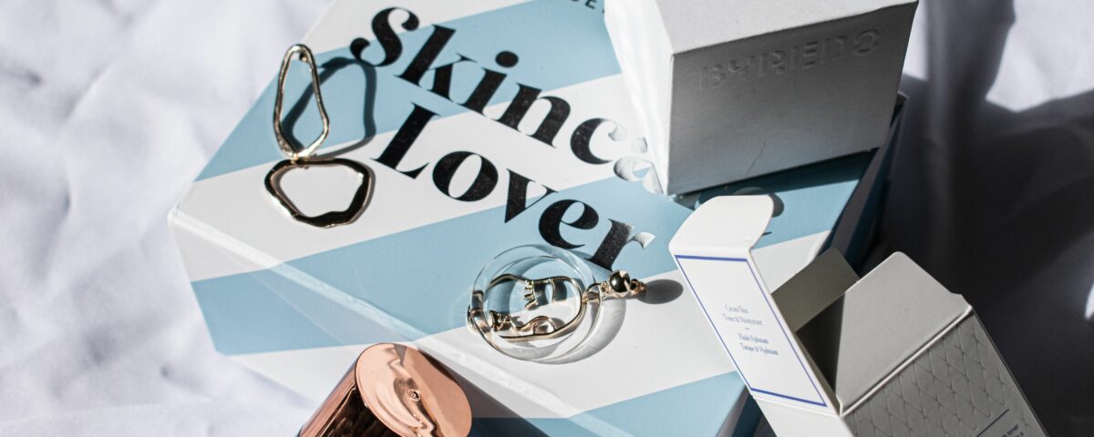 Export cosmétique : coffrets de soins, flacon et bijoux dorés sur un drap blanc
